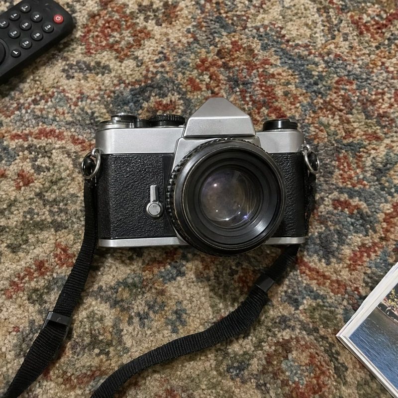 A film camera on a patterned rug next to a TV remote